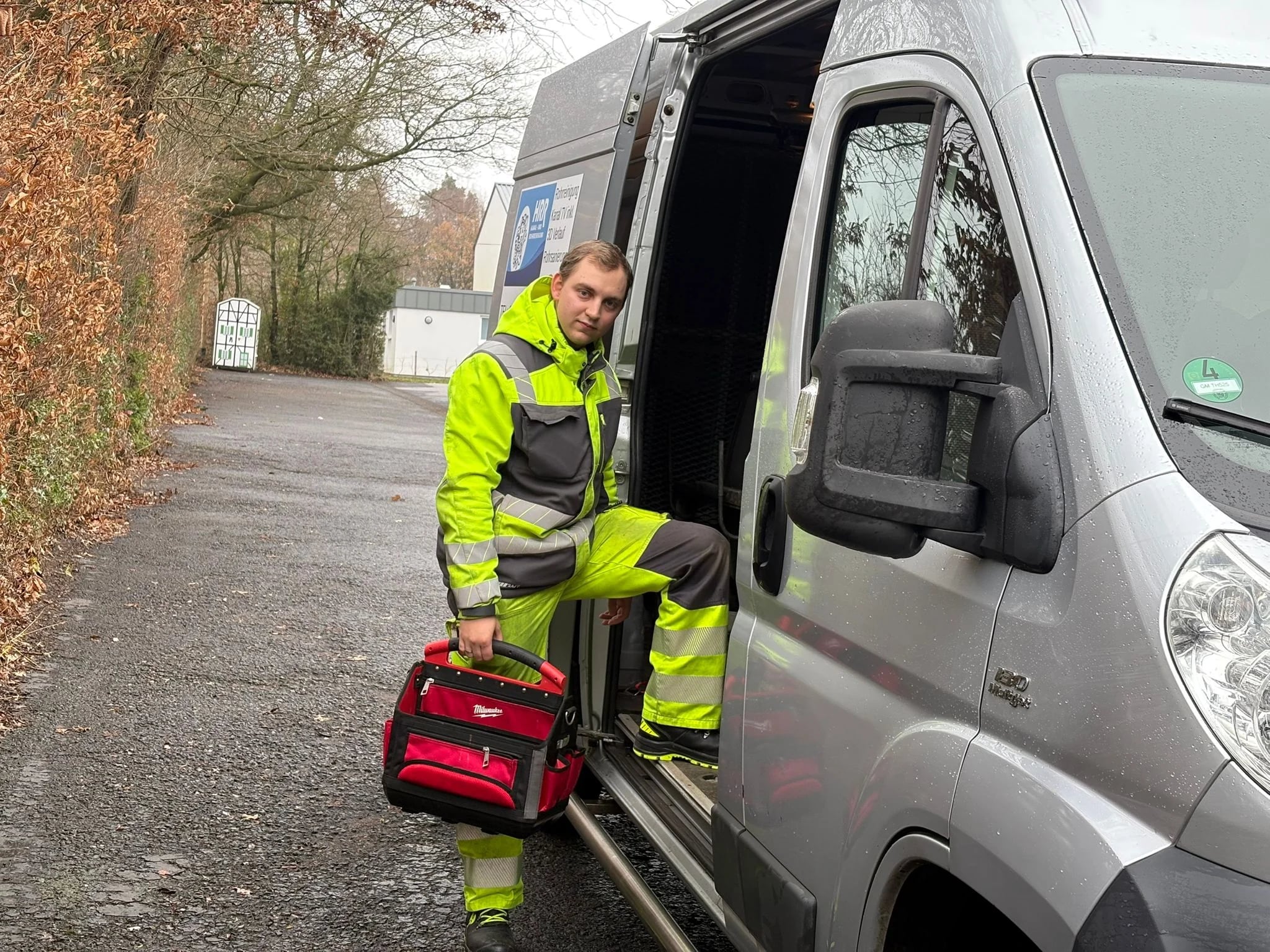 Mitarbeiter von HRR Rohrreinigung mit Werkzeugkoffer am Servicefahrzeug