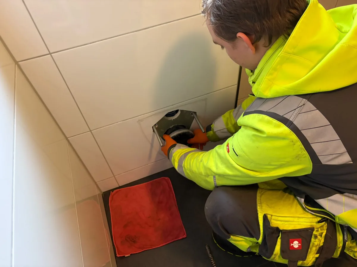 Arbeit an einer bodennahen Rohröffnung mit Schutzhandschuhen
