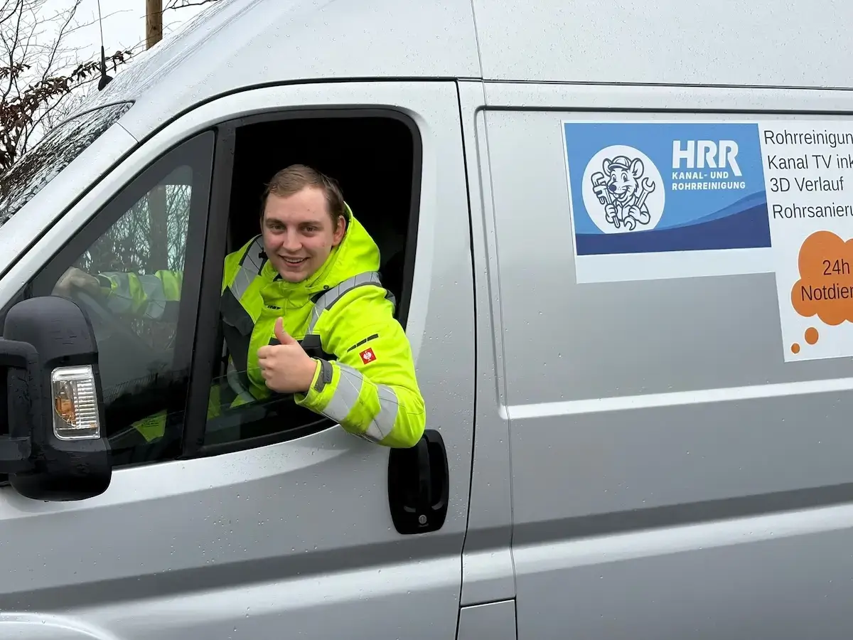 Techniker von HRR Rohrreinigung am Steuer des Einsatzfahrzeugs zeigt den Daumen nach oben