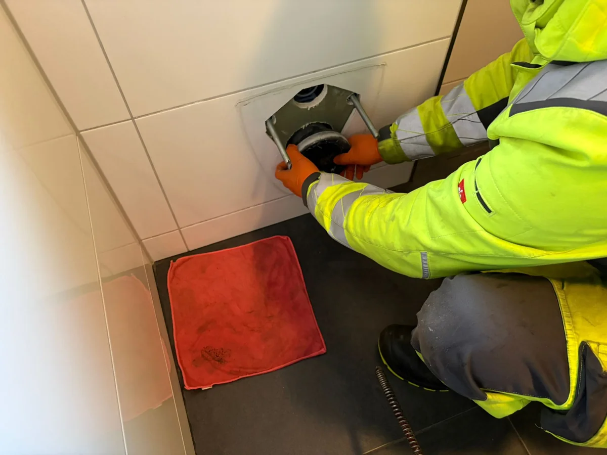 Mitarbeiter von HRR Rohrreinigung fuehrt Geraet in eine geoeffnete Rohrleitung ein