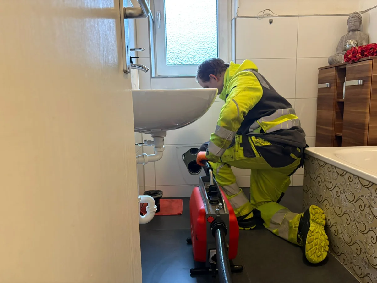 Mitarbeiter von HRR Rohrreinigung arbeitet an einer bodennahen Rohroeffnung