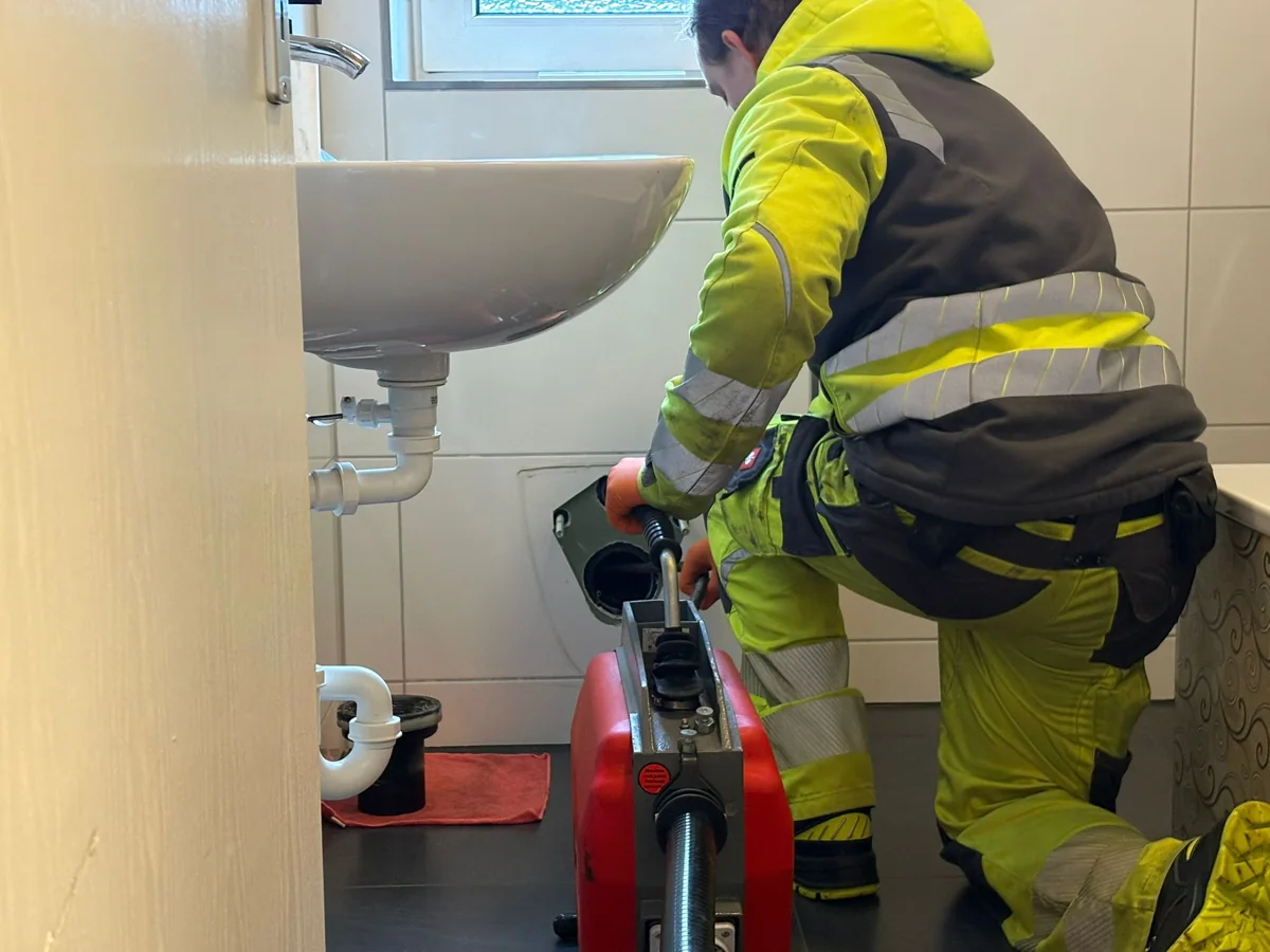 Mitarbeiter von HRR Rohrreinigung reinigt einen Waschbeckenabfluss mit der Rohrreinigungsmaschine
