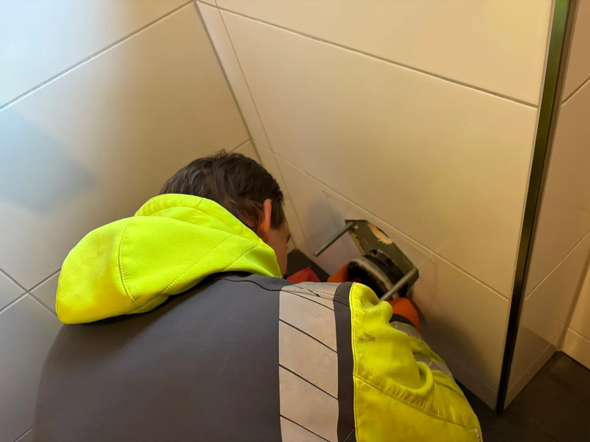 Mitarbeiter von HRR Rohrreinigung arbeitet an einer bodennahen Rohroeffnung